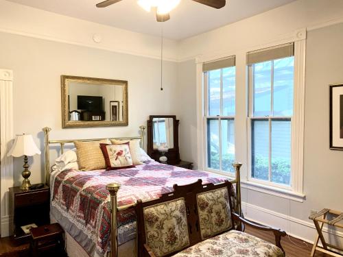 a bedroom with a bed and a mirror and windows at Brackenridge House Bed and Breakfast in San Antonio