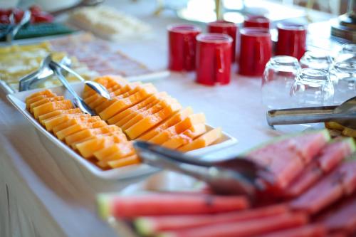 a table topped with plates of food with tongs at Aliko Hotel in Vlorë