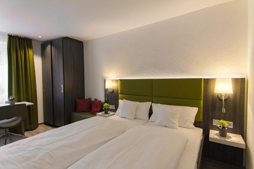 a bedroom with a large white bed with a green headboard at Insel-Hotel-Lindau in Lindau