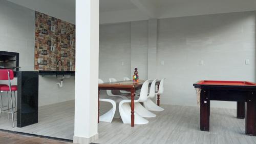 a dining room with a table and white chairs at pousada 3 Marias in Itacaré
