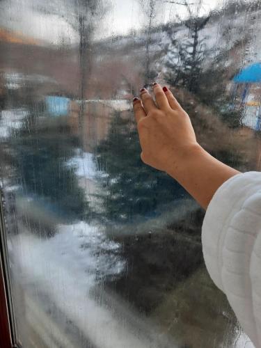 a person looking out of a window with their hand on the glass at HUMSON BULOQ SANATORIUM in Khumson