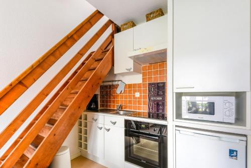 a kitchen with white cabinets and a staircase at Le Voilier in Courseulles-sur-Mer