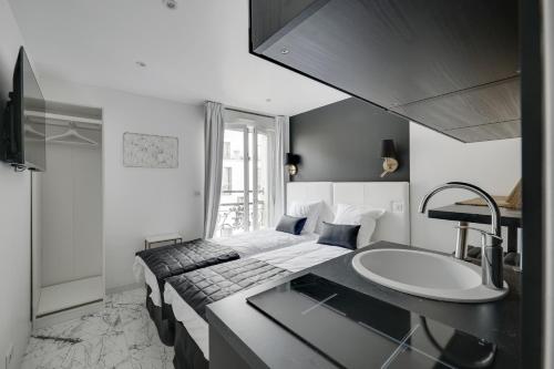 Cette chambre comprend un lavabo et un lit. dans l'établissement Le Bellevue, à Paris