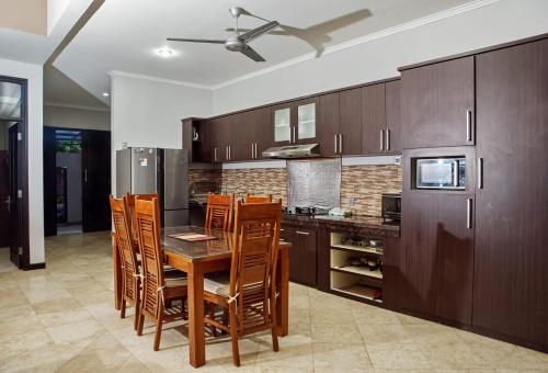 una cocina con armarios de madera, mesa y sillas en 4 BEDROOM VILLA KUTA REGENCY B10 en Kuta