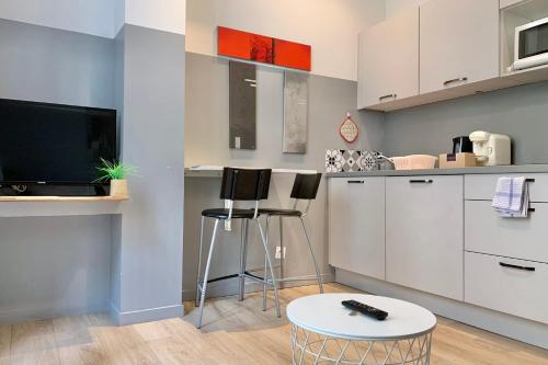 a kitchen with white cabinets and a tv and a table at Sébastien's studio Calm Fully equipped #A2 in Grenoble