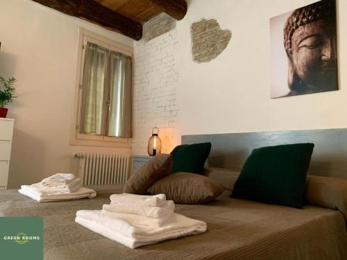 a room with a bed with towels on it at Green Rooms Ferrara in Ferrara