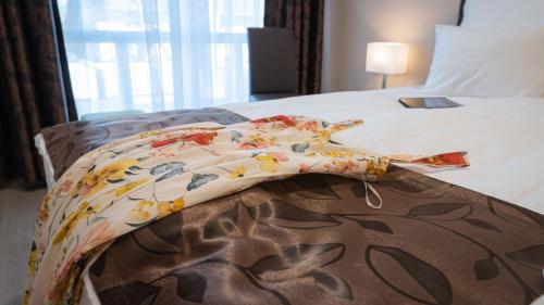a bed with a flowered blanket on top of it at Budapest Airport Eprespark Hotel in Vecsés