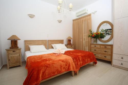 a bedroom with a bed with a orange blanket at Pension Anna in Naousa