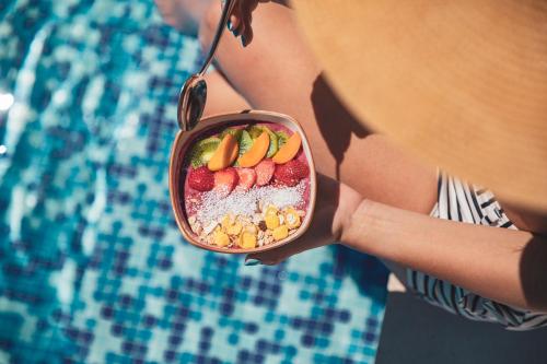 a woman holding a bowl of fruit next to a pool at Marvie Hotel & Health in Split
