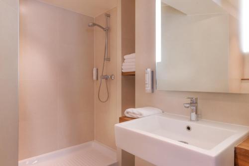 a white bathroom with a sink and a shower at Maison Axel Opéra Paris in Paris