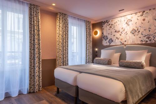 a bedroom with a large white bed and windows at Maison Axel Opéra Paris in Paris