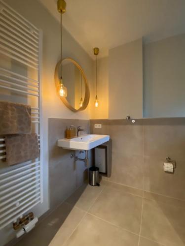 ein Bad mit einem Waschbecken und einem Spiegel in der Unterkunft Ferienappartements Bergen in Steinhude