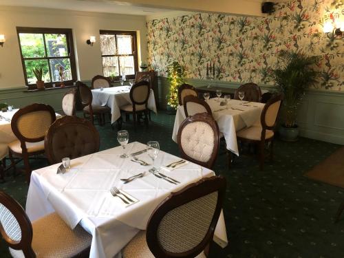 un restaurant avec tables et chaises et nappes blanches dans l'établissement The Swan Inn, à Sturminster Newton