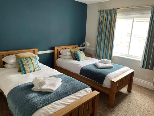 The Swan Inn في ستورمنستر نيوتن: سريرين في غرفة بجدران زرقاء ونافذة