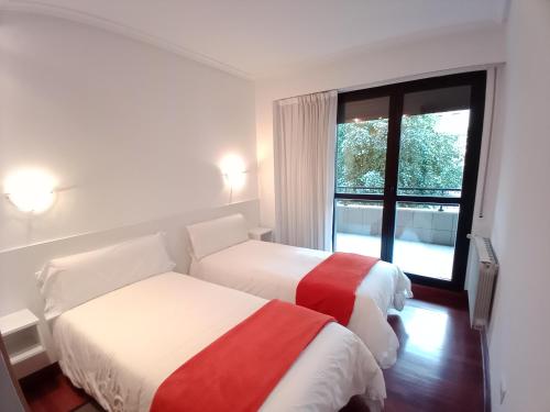 dwa łóżka w pokoju z oknem w obiekcie Apartamento Ana Elgoibar con garaje w mieście Elgoibar