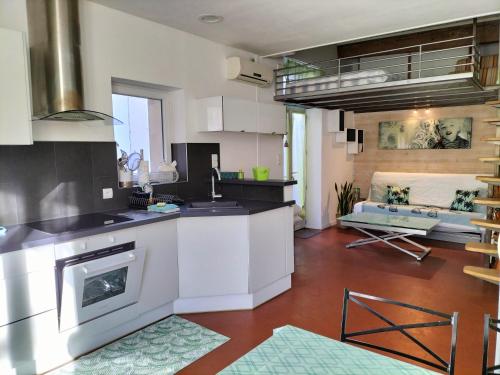 une cuisine avec des armoires blanches et un salon dans l'établissement STUDIO CLIMATISE avec MEZZANINE au calme avec terrasse et parking idéalement situé pour tout faire à pied !, à Bandol