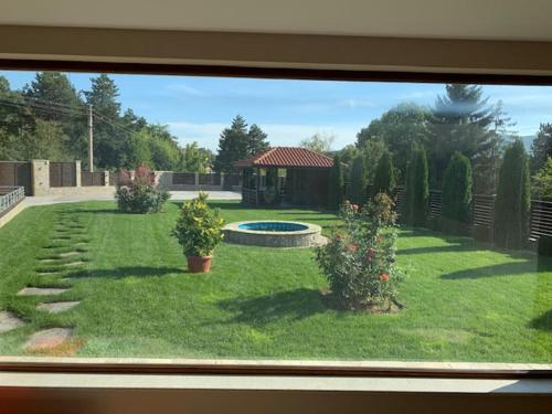 a window view of a yard with a garden with a pool at Луксозна вила - Стрелча, джакузи с минерална вода in Strelcha