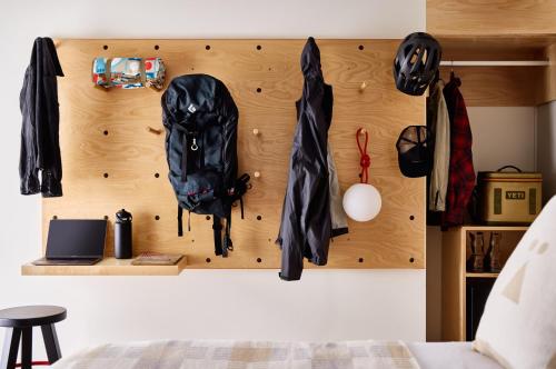 a wall with coats and umbrellas hanging on it at Tälta Lodge, a Bluebird by Lark in Stowe