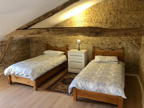 a bedroom with two beds and a stone wall at Les Roches in Vanzay