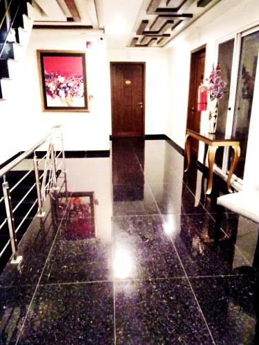 a hallway with black tile floors and a staircase at Jade Dragon Hotel DHA Lahore in Lahore