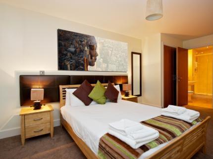 a bedroom with a large white bed and a night stand at Arcadian Aparthotel in Birmingham