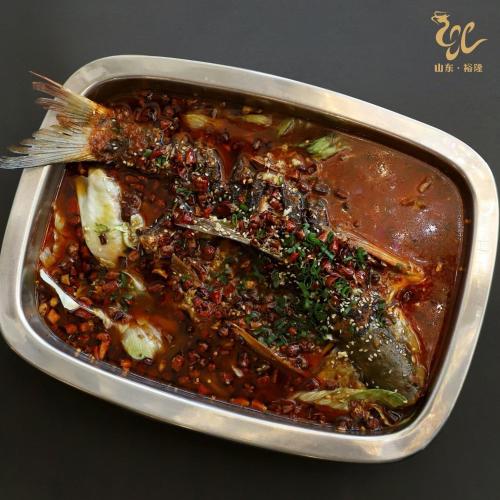 a metal dish of food with a fish and beans at Jade Dragon Hotel DHA Lahore in Lahore