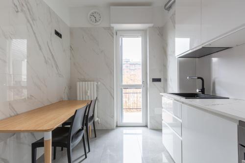 cocina blanca con mesa de madera y fregadero en BnButler - Largo Promessi Sposi - Moderno e Confortevole, en Milán