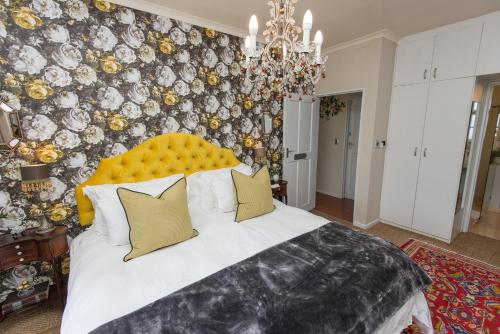a bedroom with a large bed with a yellow headboard at Baruch Guest House in Stellenbosch