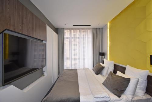 a bedroom with a large bed with a large flat screen tv at Avenue ApartHotel in Yerevan
