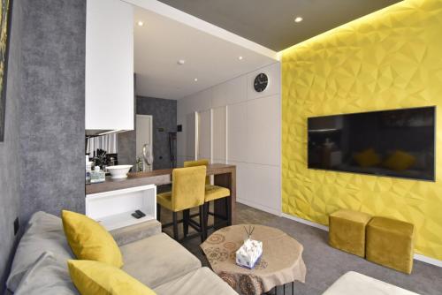 a living room with a couch and a table with yellow chairs at Avenue ApartHotel in Yerevan