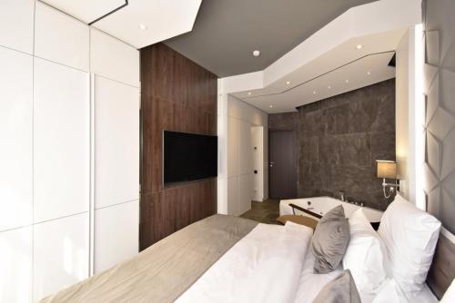 a bedroom with a large white bed and a tv at Avenue ApartHotel in Yerevan