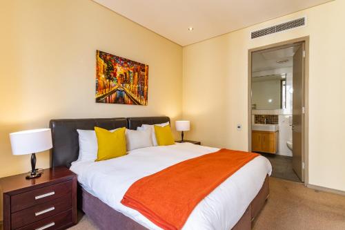 a bedroom with a large bed and a painting on the wall at Luxury Cartwrights Corner Apartments with Juliette balconies in Cape Town