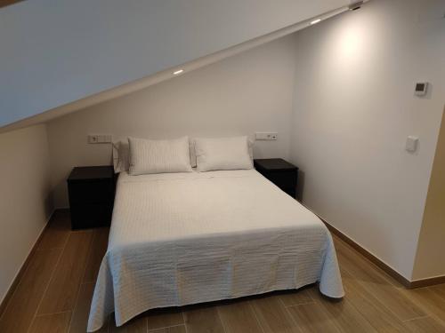 a bedroom with a bed with white sheets and pillows at Apartamentos A pousa do Asma in Chantada