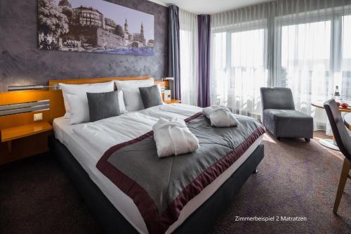 a hotel room with a large bed and a chair at Ramada by Wyndham Dresden in Dresden