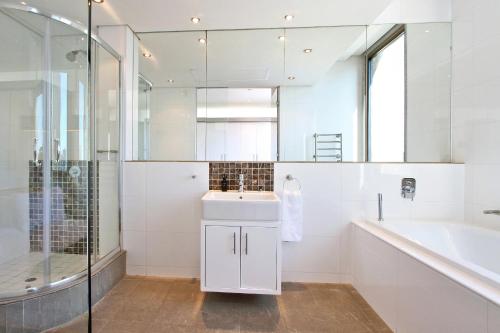 bagno con lavandino, vasca e doccia di Luxury Cartwrights Corner Apartments with Juliette balconies a Città del Capo