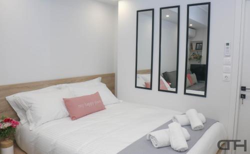 a white bed with a pink pillow and mirrors at New deluxe studio 4 downtown Thessaloniki- Fully equiped in Thessaloniki