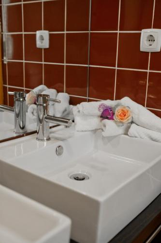 a bathroom sink with towels and a flower on it at Hotel Vila Luena in Vila Verde