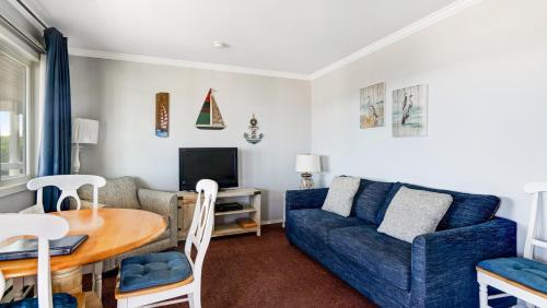 a living room with a blue couch and a table at Montauk Oceanside Suites in Montauk