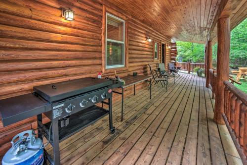 a front porch of a log cabin with a grill at Updated Manistique Log Cabin, Yard and Fire Pit in Manistique