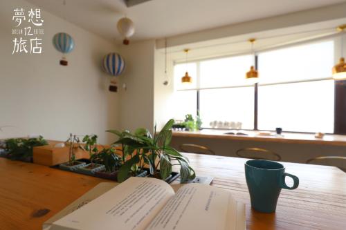an open book on a wooden table with a coffee mug at Dream 12 Hotel in Taichung
