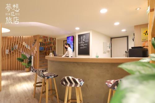 a woman standing at a counter in a restaurant with stools at Dream 12 Hotel in Taichung