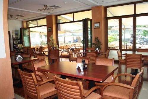 a restaurant with wooden tables and chairs and windows at Paradise Hotel & Relax Center in Pomorie