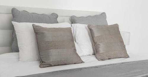 a white bed with four pillows on it at Anoud Manor in Hout Bay
