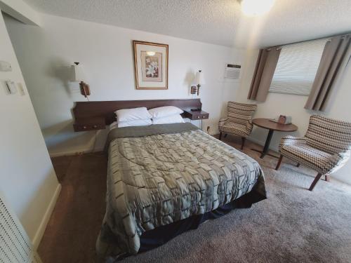 ein Schlafzimmer mit einem Bett, einem Tisch und einem Stuhl in der Unterkunft Holiday Lodge in Sheridan
