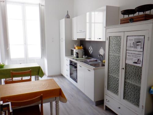 una pequeña cocina con armarios blancos, una mesa y un tocador en Sicania, en Patti