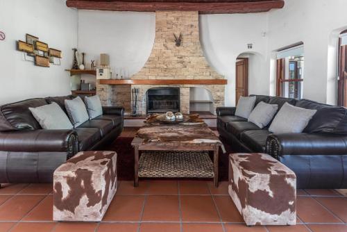 a living room with leather couches and a fireplace at Anoud Manor in Hout Bay