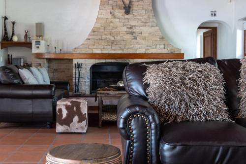a living room with a leather couch and a fireplace at Anoud Manor in Hout Bay
