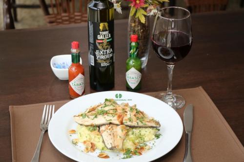 a plate of food on a table with a glass of wine at Hotel Nacional Inn São José dos Campos in São José dos Campos