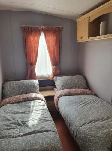 2 camas en una habitación pequeña con ventana en 64 Southfield - Skipsea Sands en Ulrome