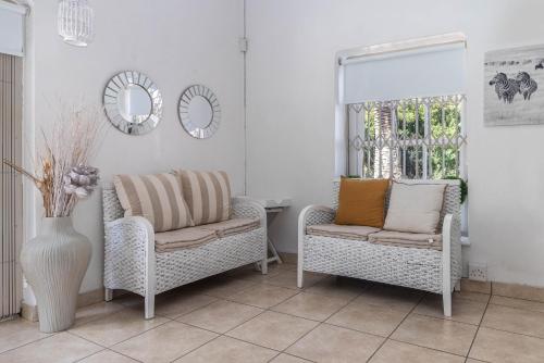 a living room with two chairs and a mirror at Anoud Manor in Hout Bay